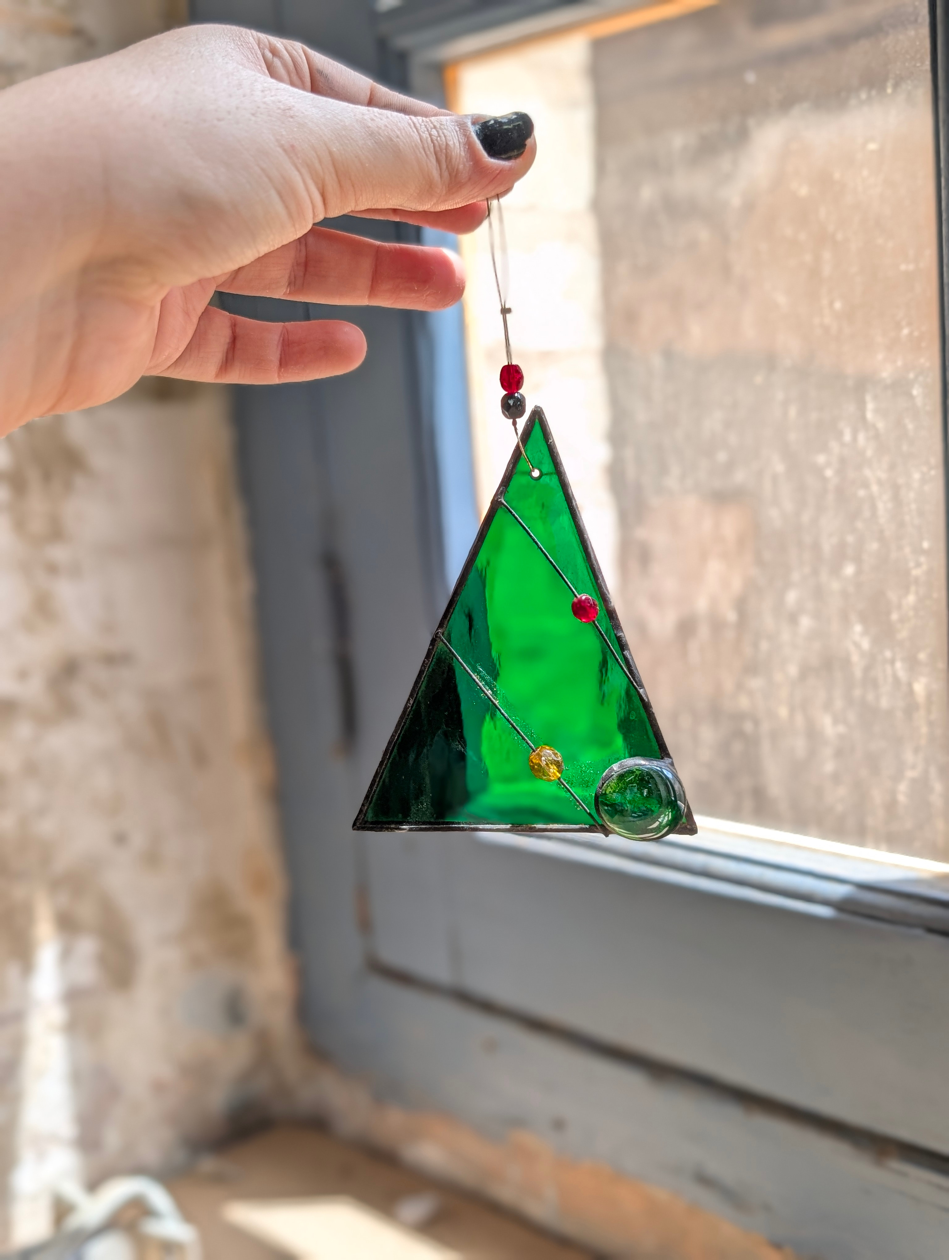 Adorno de vidriera en forma de árbol de Navidad verde, sujeto con la mano