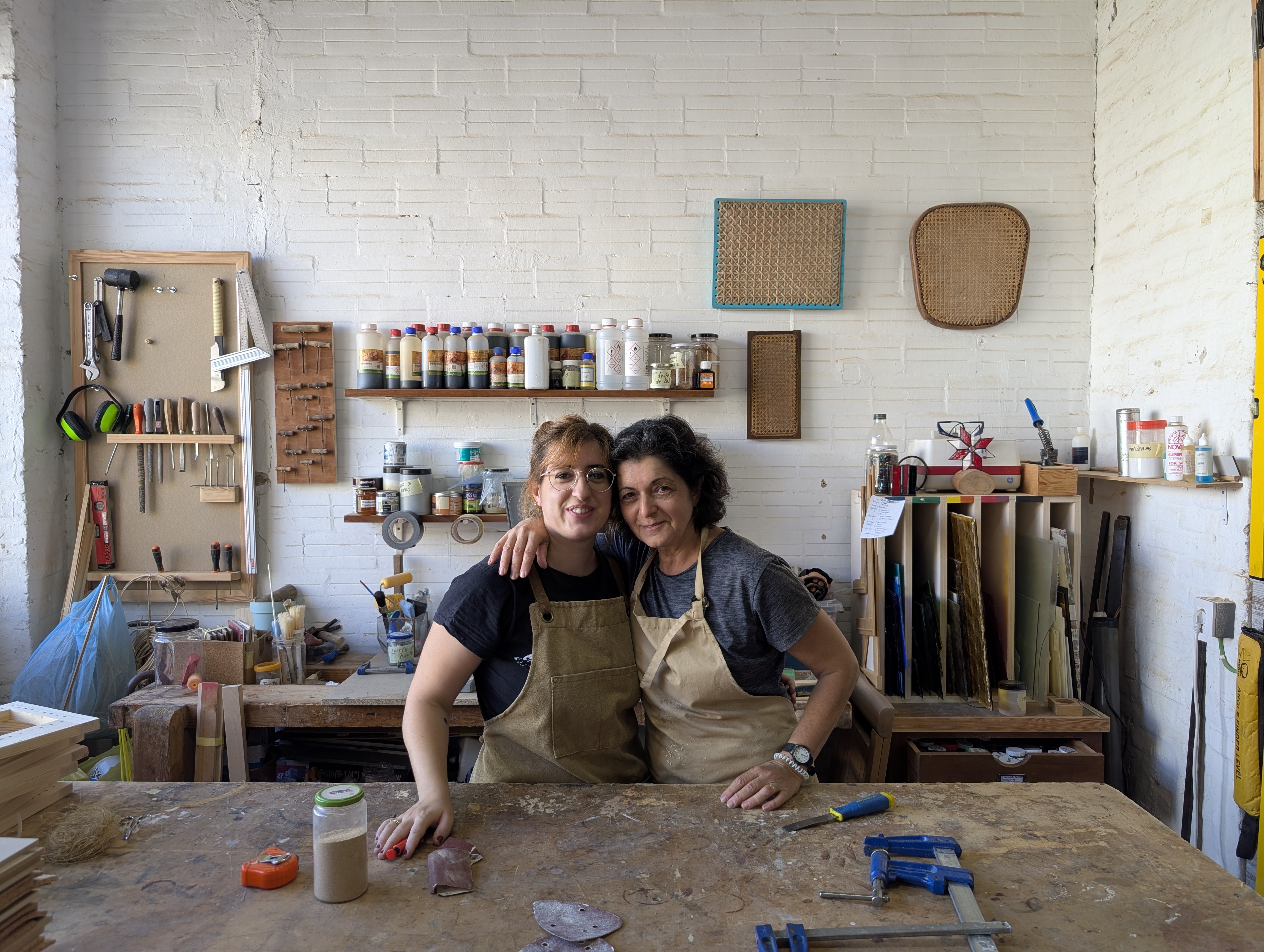 Luna y su madre abrazadas sonriendo en el taller