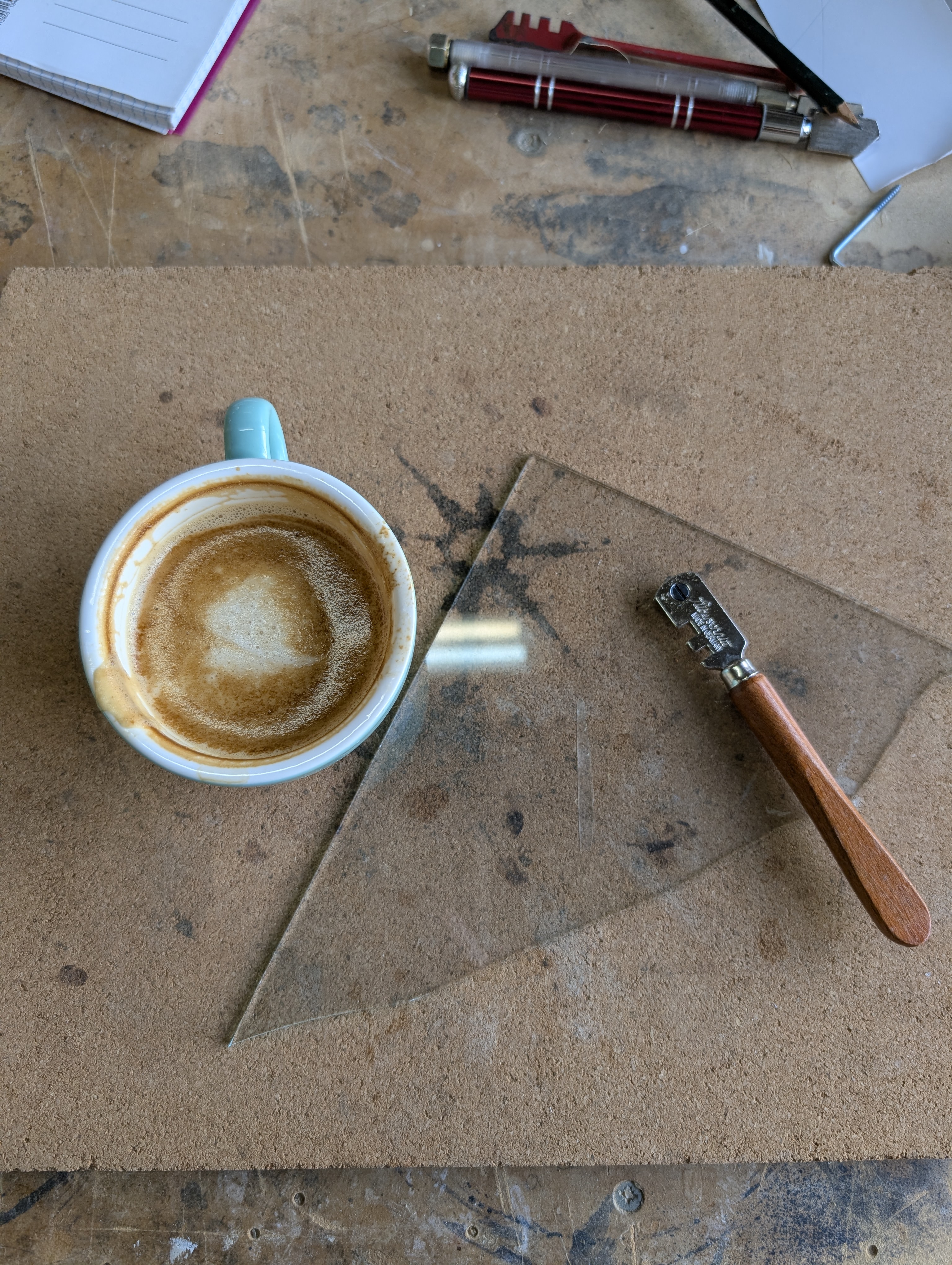 Taza de café y un cortavidrios sobre la mesa de trabajo