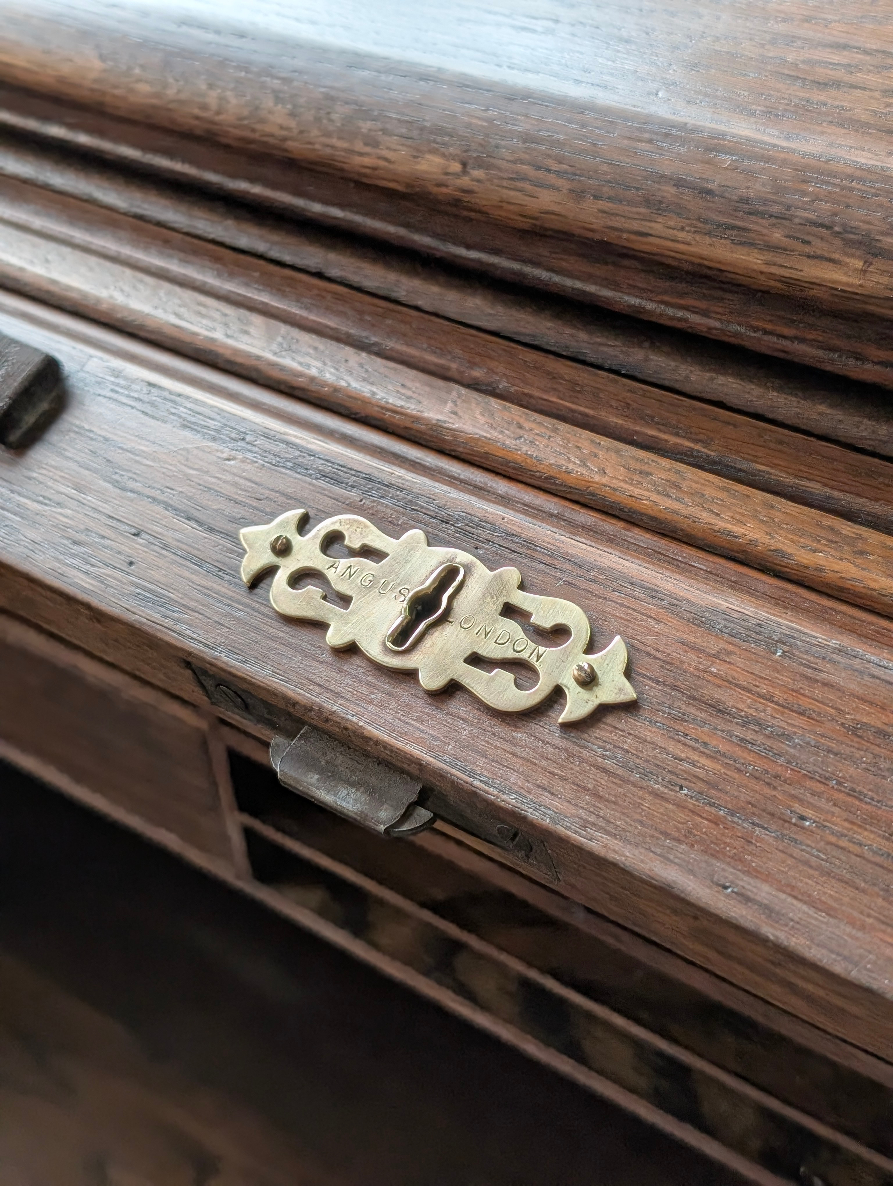 Detalle de un tirador de bronce antiguo grabado “Angus London” en un mueble restaurado