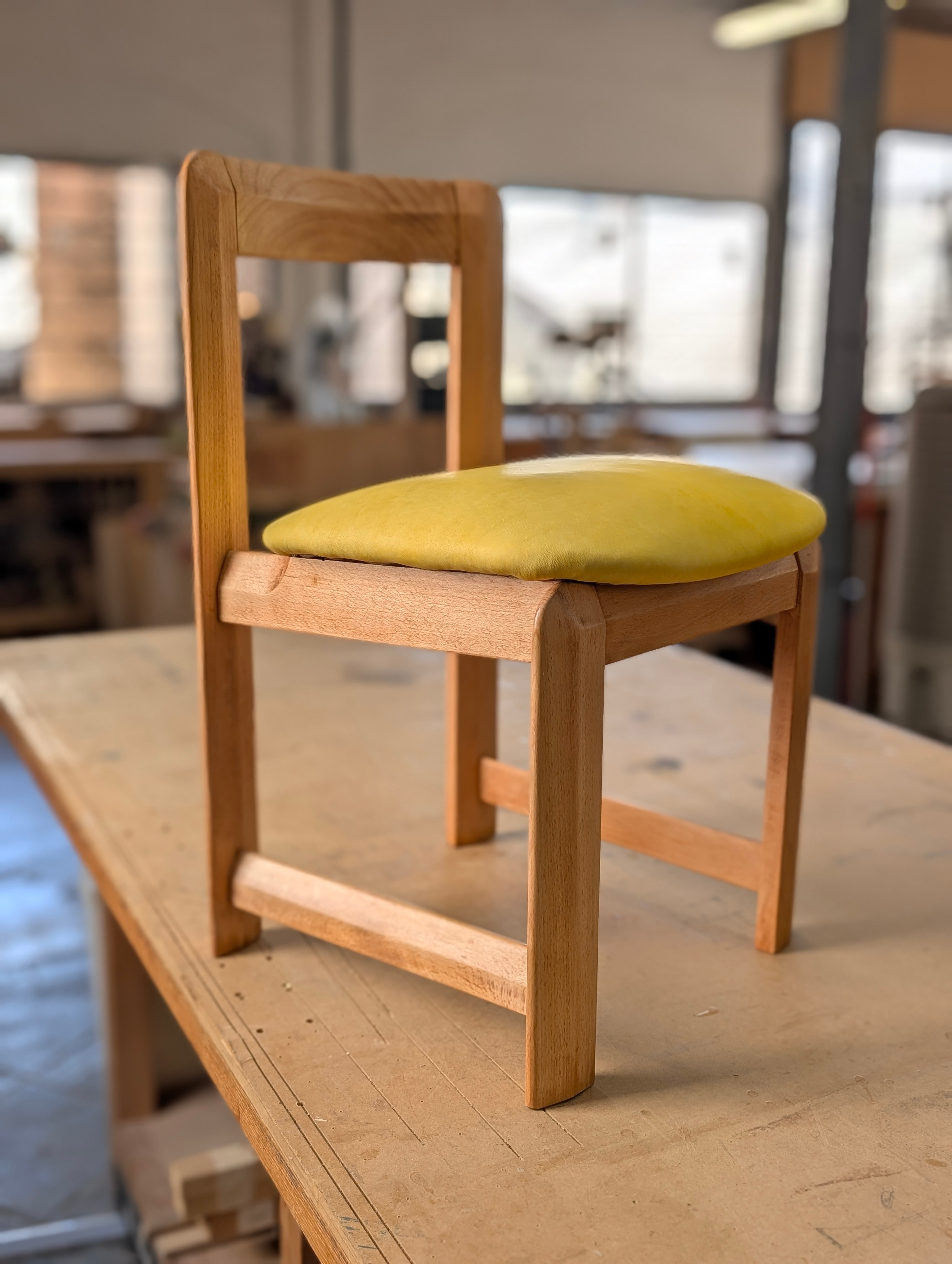 Silla de madera restaurada con un nuevo tapizado en cuero amarillo mostaza